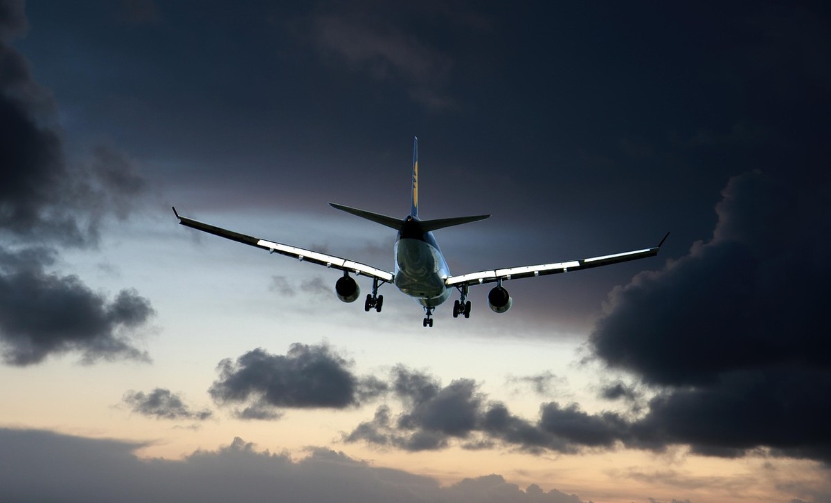 Avion décollant ou volant bas sous des nuages sombres, avec ses ailes et ses moteurs clairement visibles