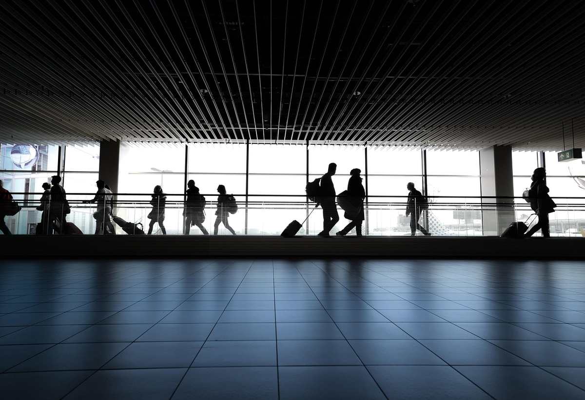 Silhouettes de voyageurs avec bagages dans un hall d'aéroport