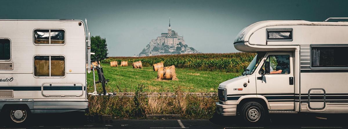 Deux véhicules de tourisme garés devant un pré avec moutons et Mont Saint-Michel