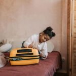 Une jeune fille emballe une valise jaune sur un lit