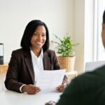 Une femme souriante en costume tient un document face à un homme en entretien